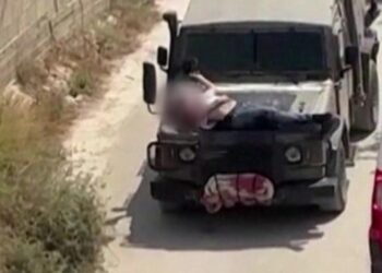 The Israeli military fastens a wounded Palestinian to a jeep during a raid.